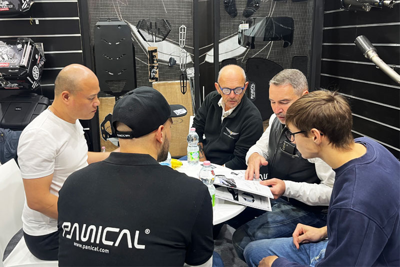 Visitors reviewing motorcycle accessory information at the PANICAL booth in Milan